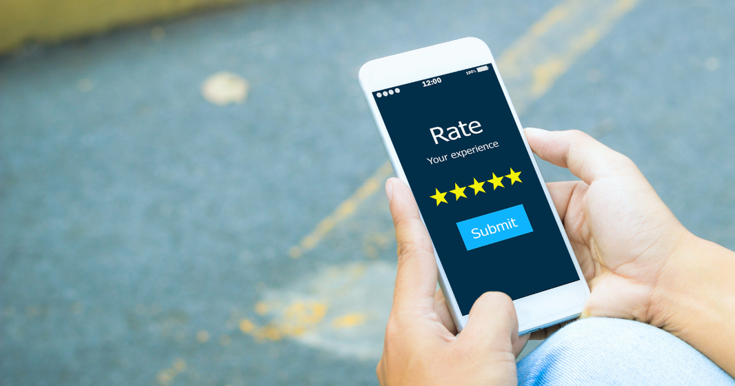 Person holding a smartphone displaying a product review screen with five-star rating and submit button.