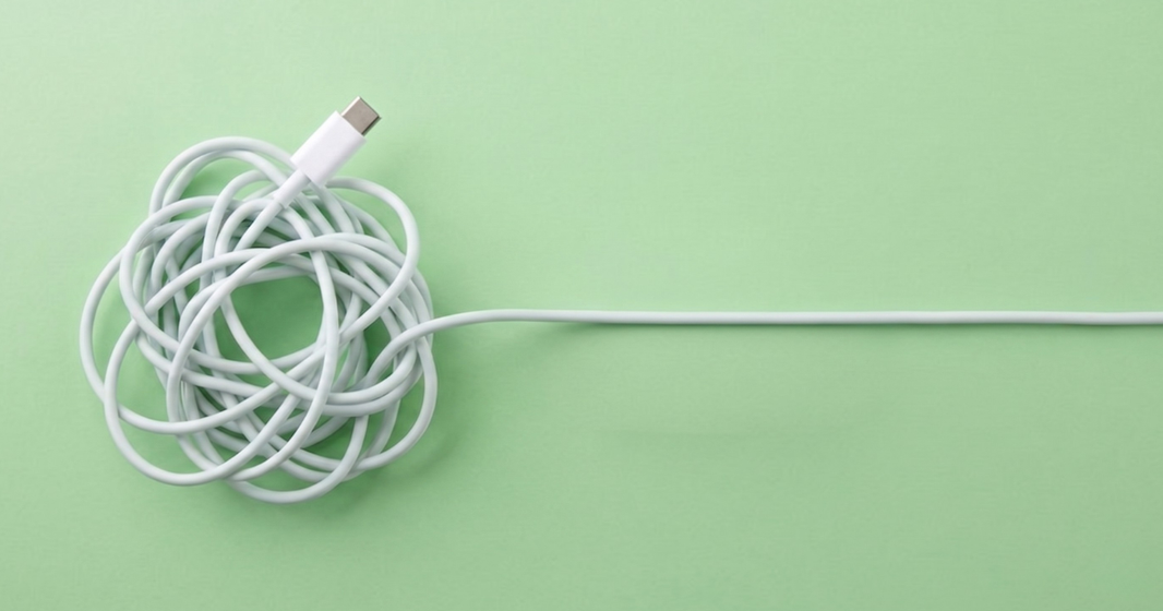 Tangled white USB-C cable transitioning into a straight cable on a green background, illustrating the simplification of a complex system.