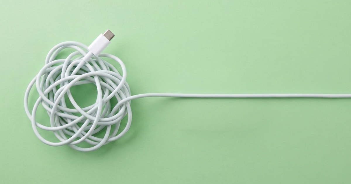 Tangled white USB-C cable transitioning into a straight cable on a green background, illustrating the simplification of a complex system.