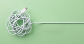 Tangled white USB-C cable transitioning into a straight cable on a green background, illustrating the simplification of a complex system.