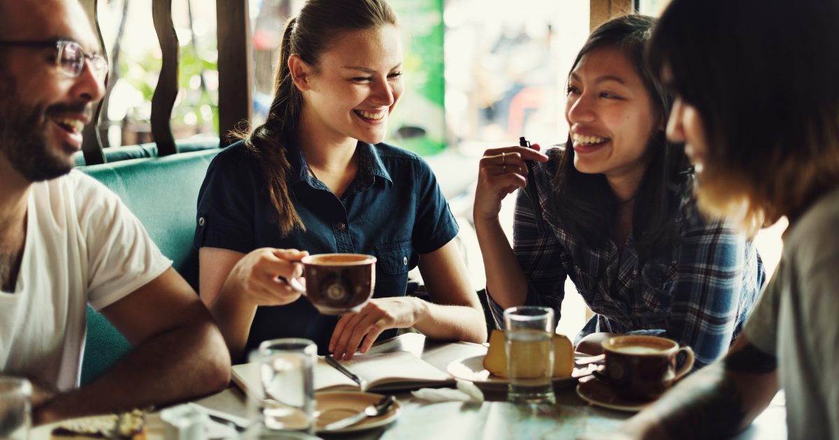 Four friends enjoying coffee, snacks and conversation at a coffee shop.