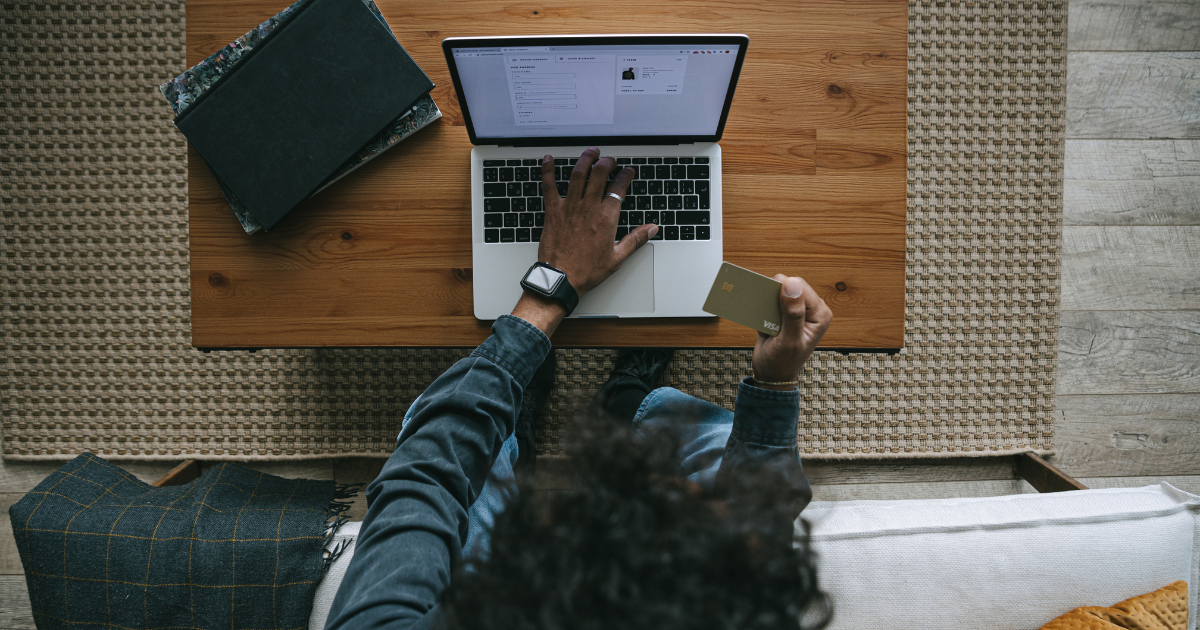 Shopper holding a credit card while completing an ecommerce purchase on a laptop.
