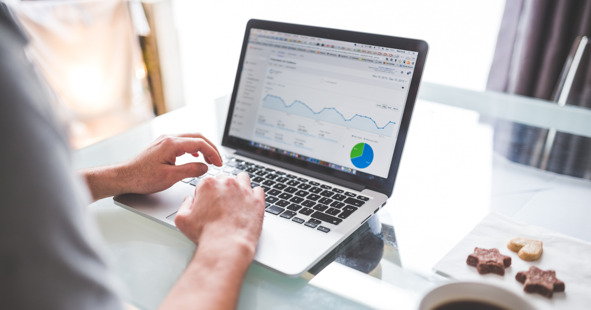 Person using a laptop with financial charts on a desk