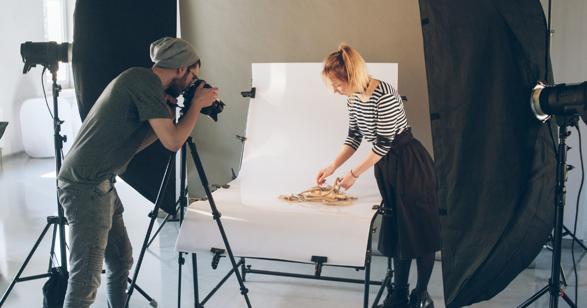 Photographer and stylist arranging products during a professional studio shoot.